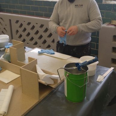 Eine Person bereitet Materialien für eine handwerkliche Tätigkeit auf einem Tisch vor.